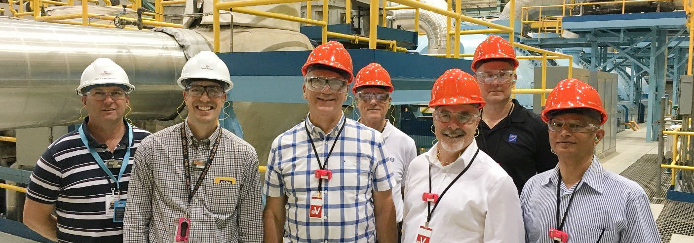 Seven people in hard hats in a turbine hall